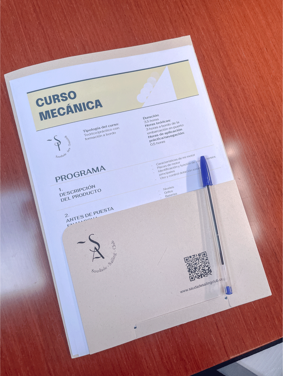 Sobre una mesa de madera hay un documento titulado "Curso de Navegación: Mecánica" con un bolígrafo colocado encima. El documento incluye un programa del curso impreso y un sobre marrón con logo y código QR, ideal para quienes buscan formación a bordo en La Marina de València.