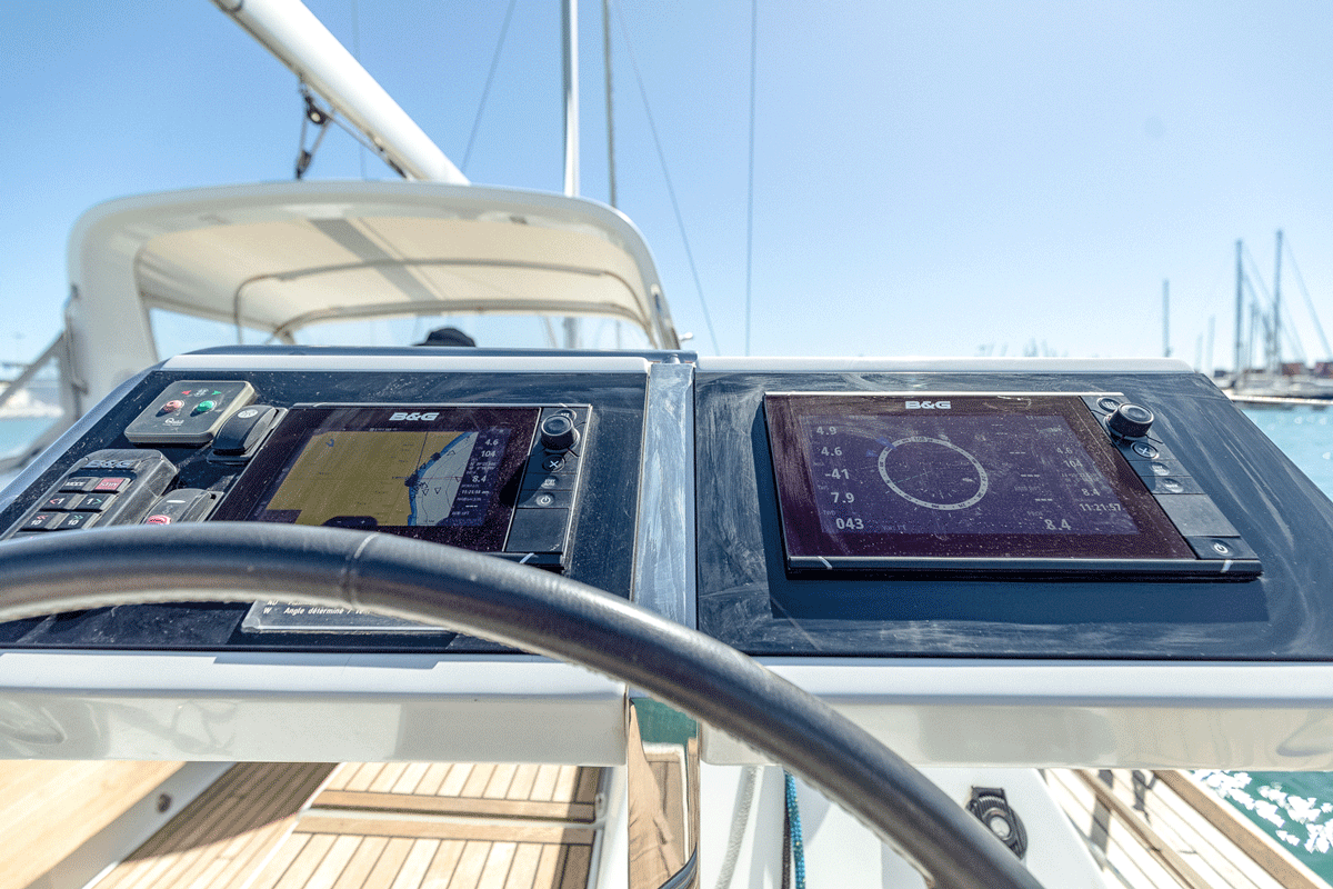 Vista cercana del panel de control y navegación de un velero, con pantallas y equipos digitales avanzados bajo un cielo despejado en La Marina de València. Ideal para el "Curso de Navegación: Cartas náuticas y plotter", brindando instrucción en clase y capacitación práctica a bordo.